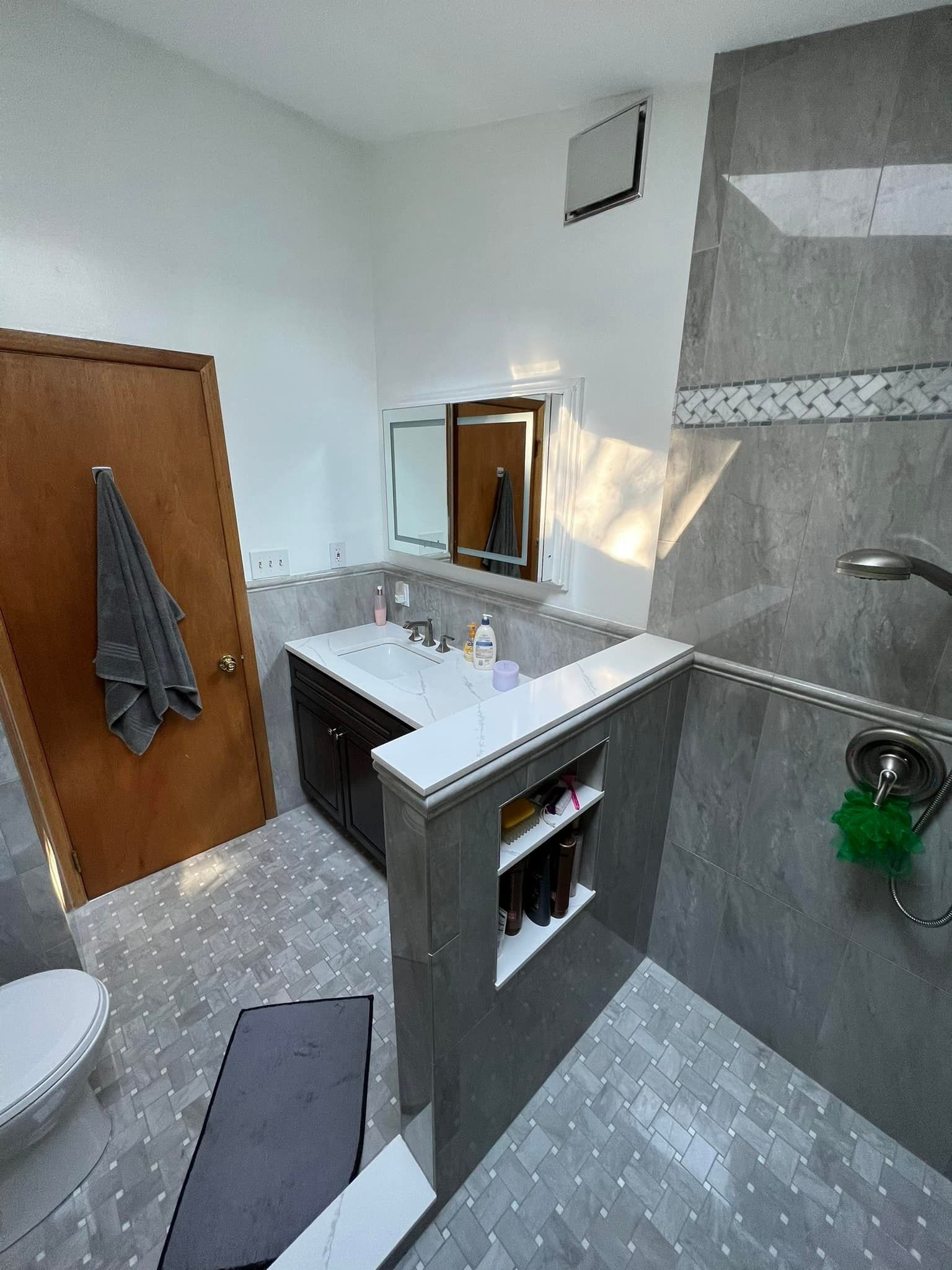 A bathroom with a toilet , sink , mirror and shower.