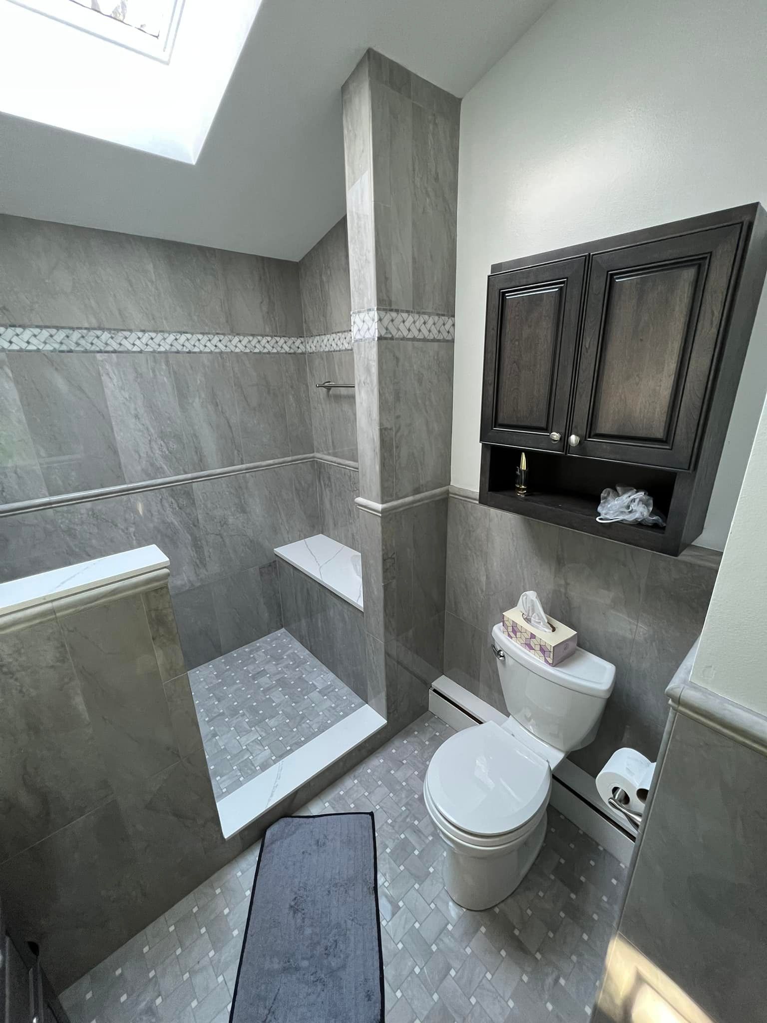 A bathroom with a toilet , shower , and cabinets.