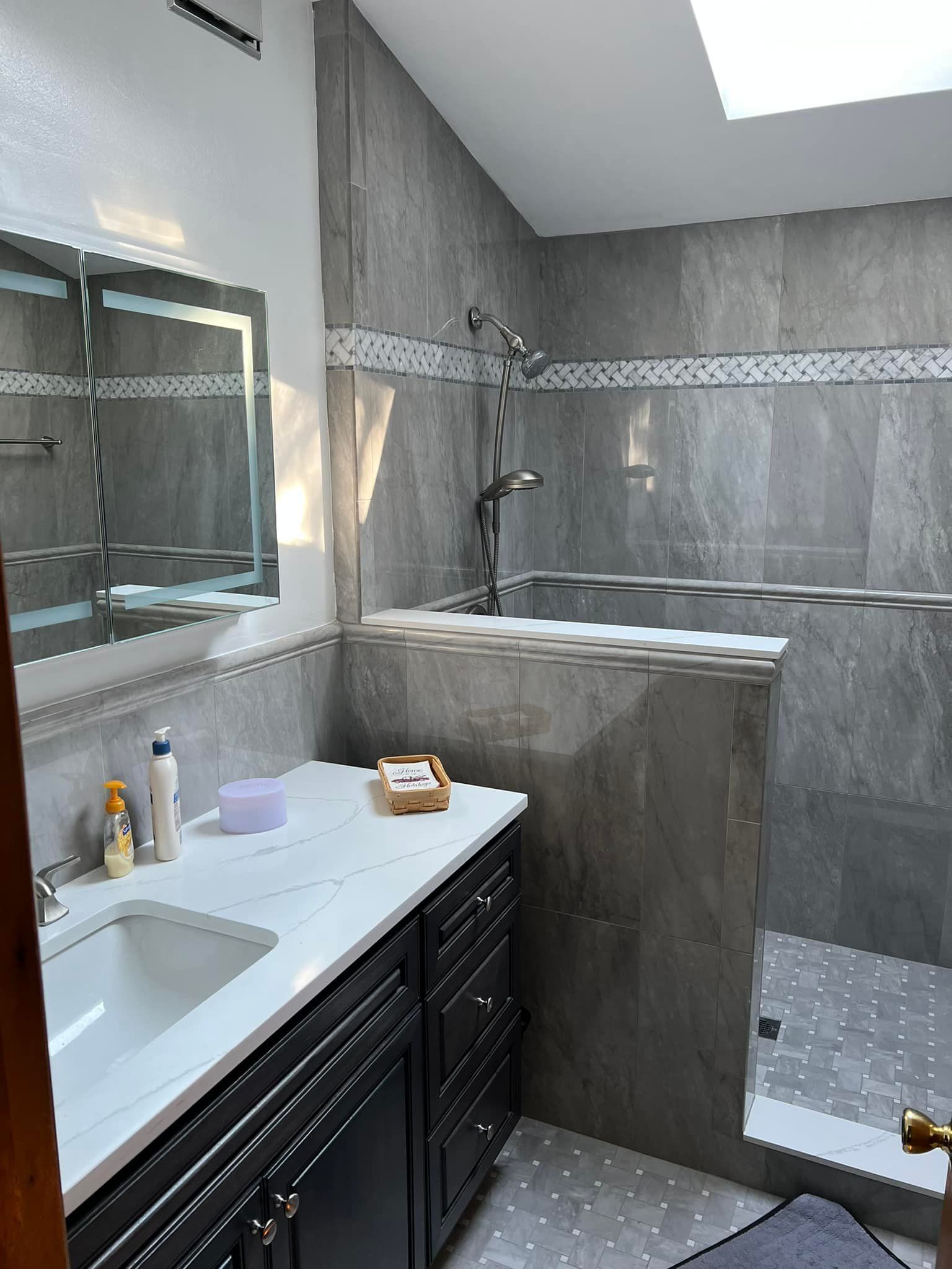 A bathroom with a sink , mirror , tub and shower.