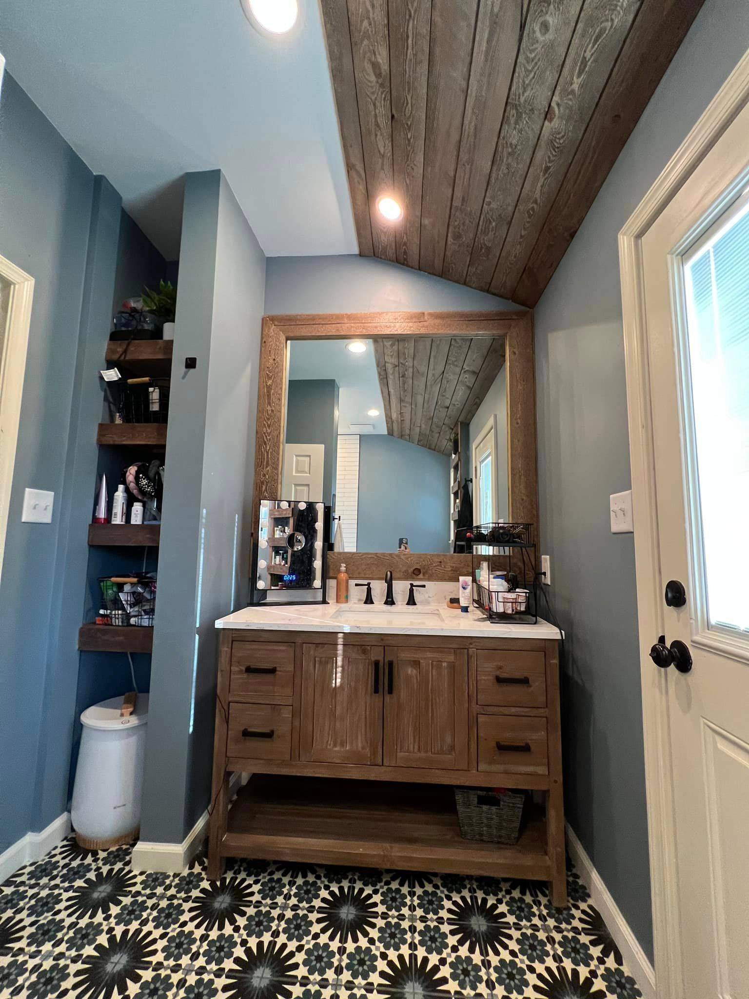 A bathroom with a wooden vanity and a large mirror.