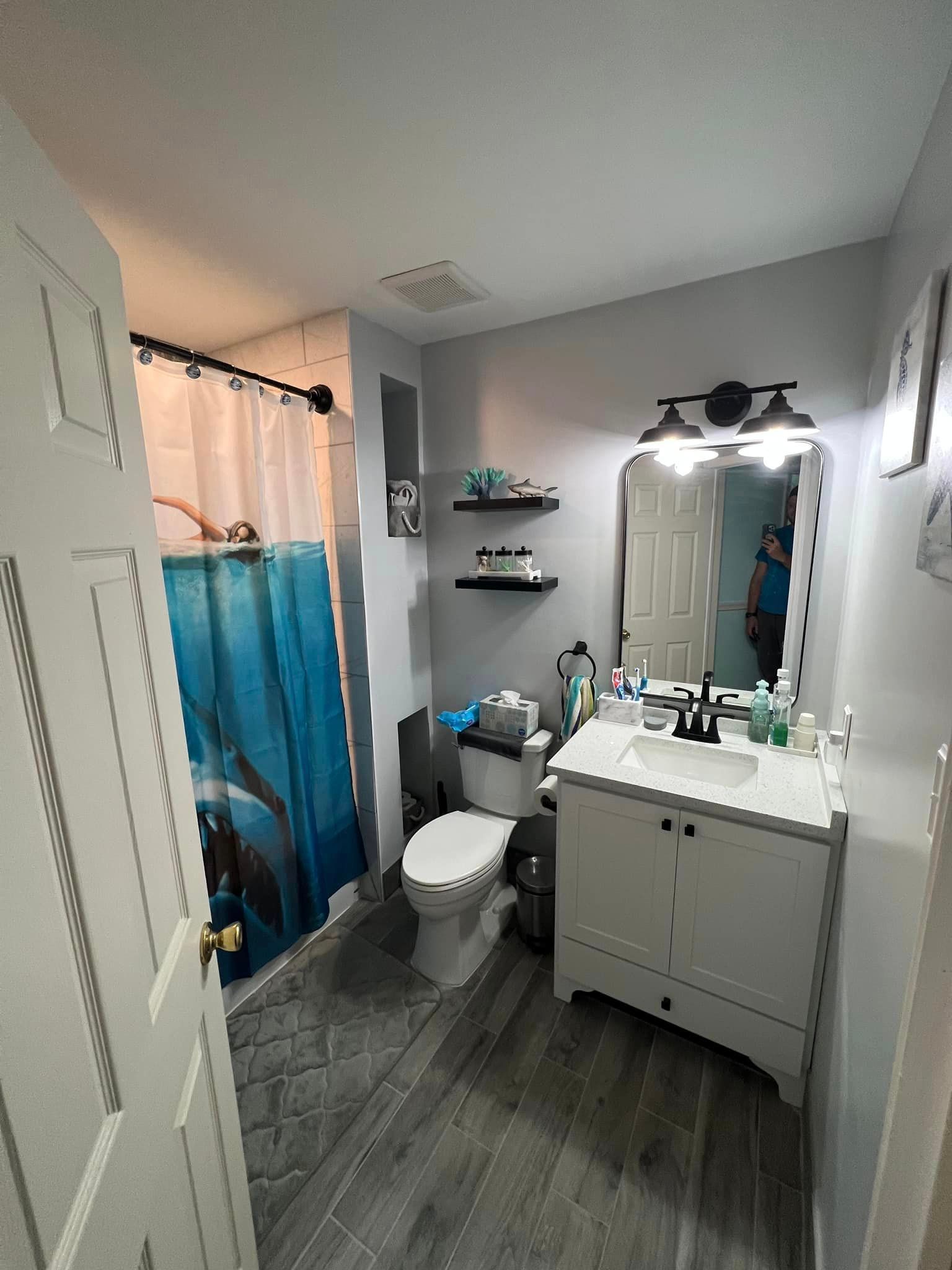 A bathroom with a toilet , sink , mirror and shower curtain.