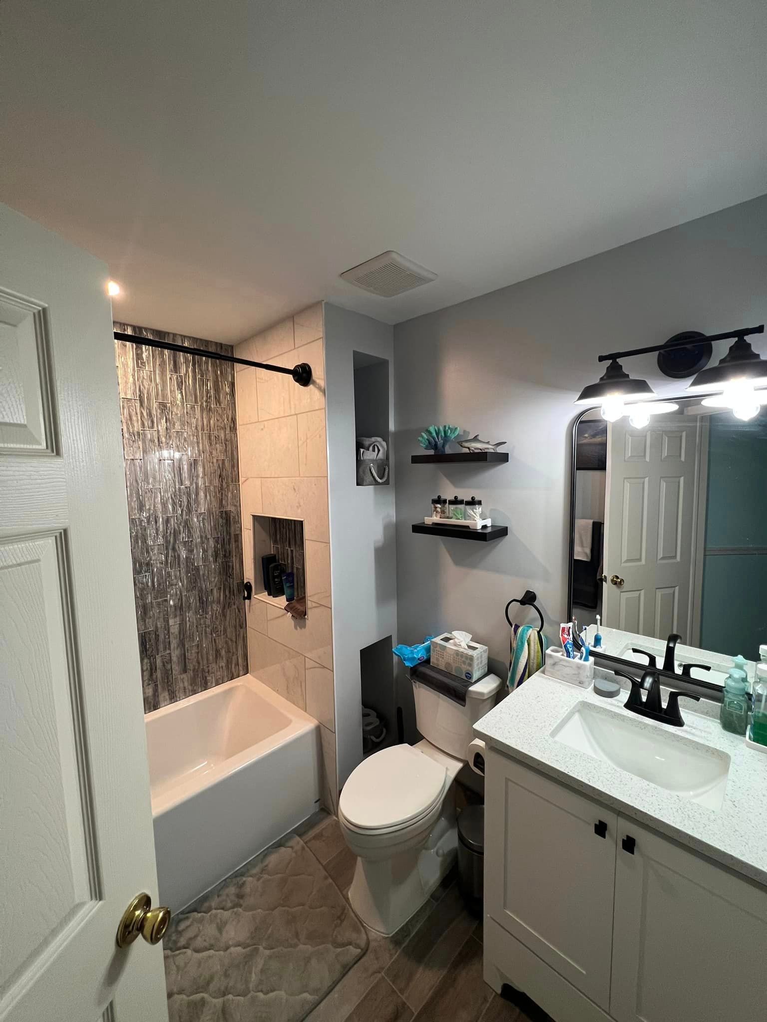 A bathroom with a toilet , sink , bathtub and mirror.