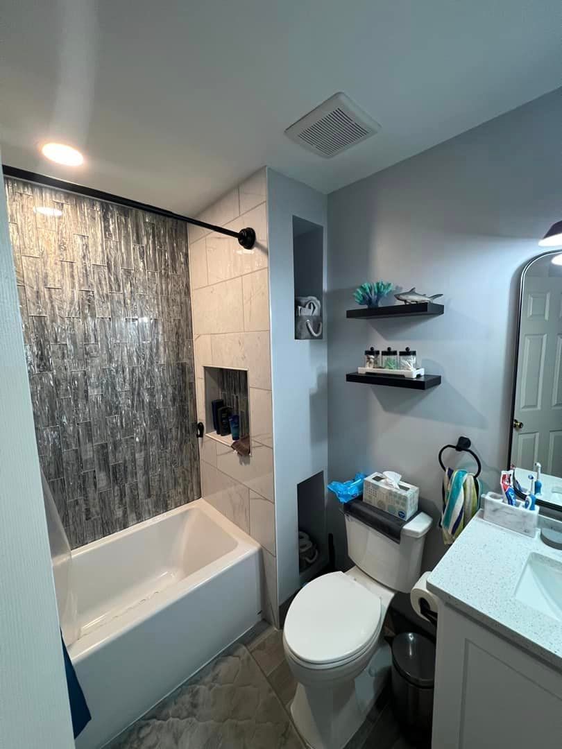 A bathroom with a tub , toilet , sink and mirror.