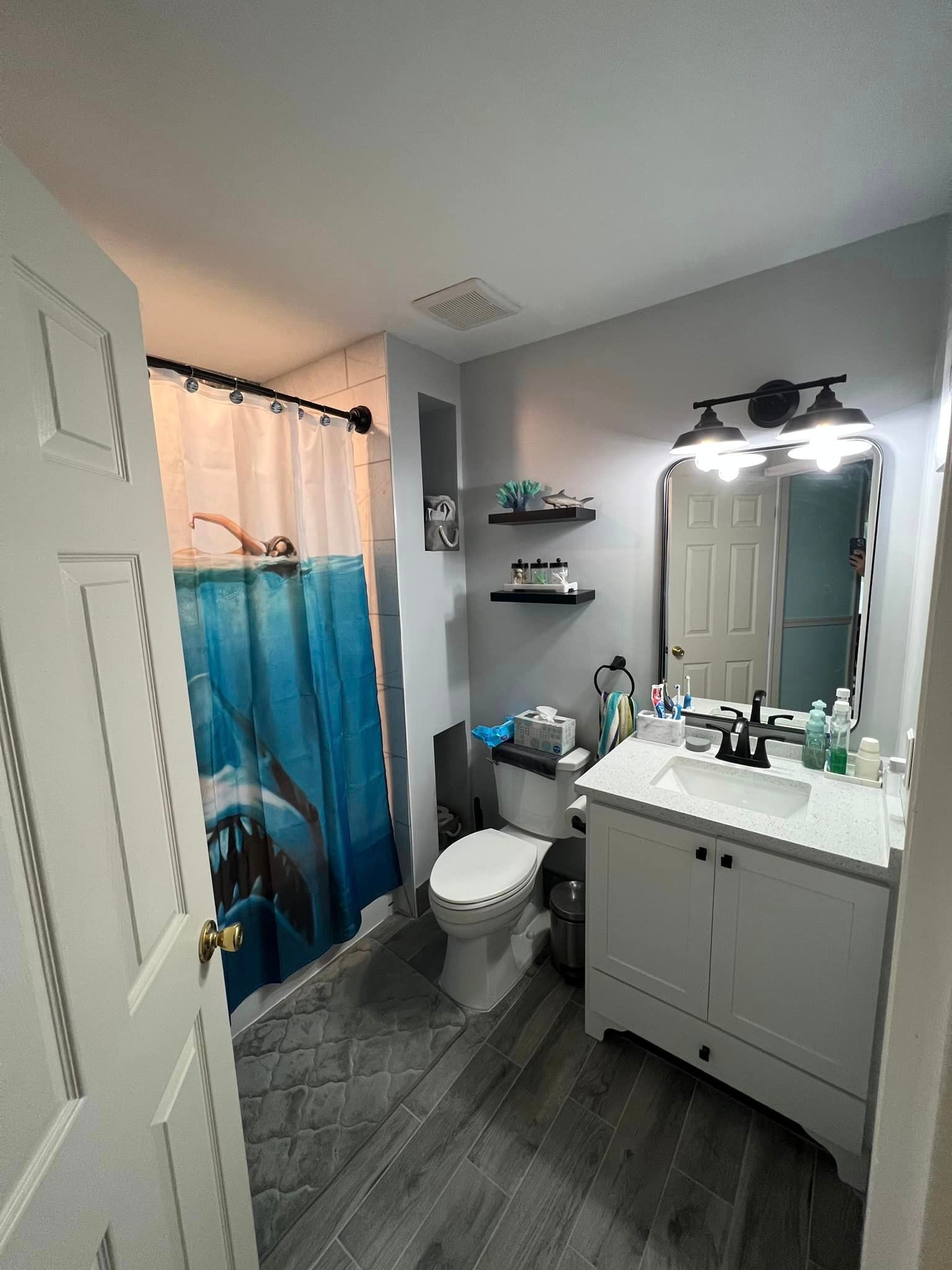 A bathroom with a toilet , sink , mirror and shower curtain.