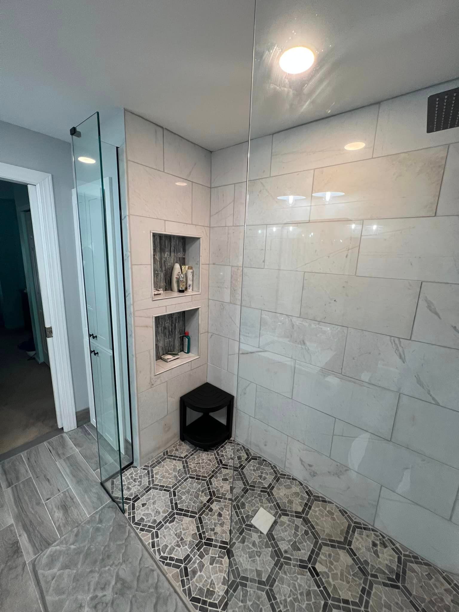 A bathroom with a walk in shower and a glass door.