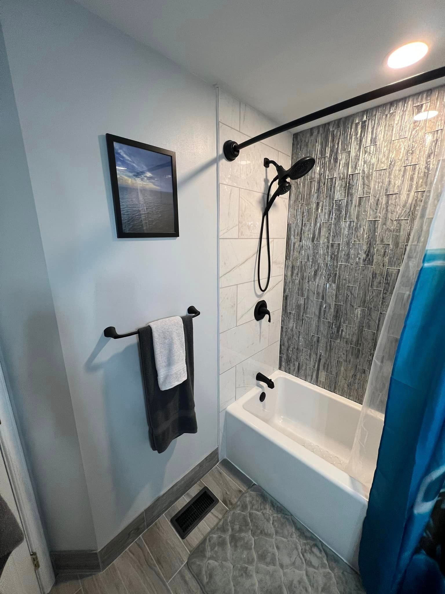 A bathroom with a bathtub , shower , and towel rack.