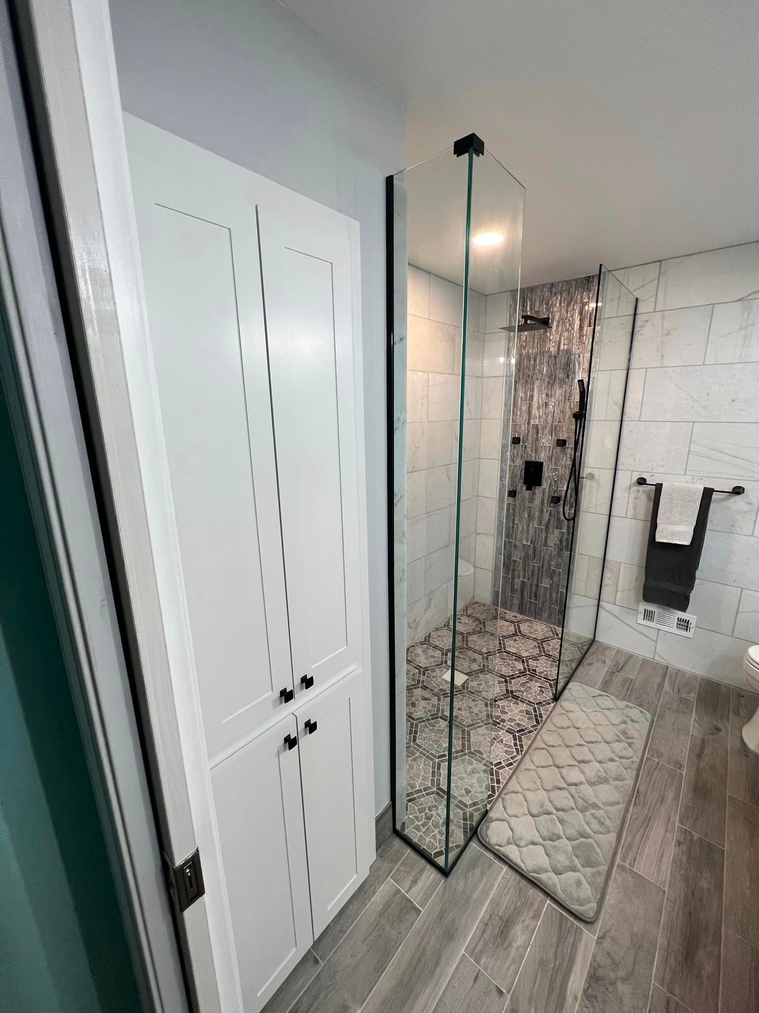 A bathroom with a walk in shower and a closet.