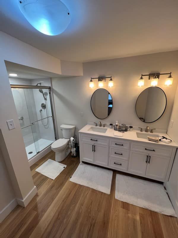 A bathroom with two sinks , a toilet and a shower.