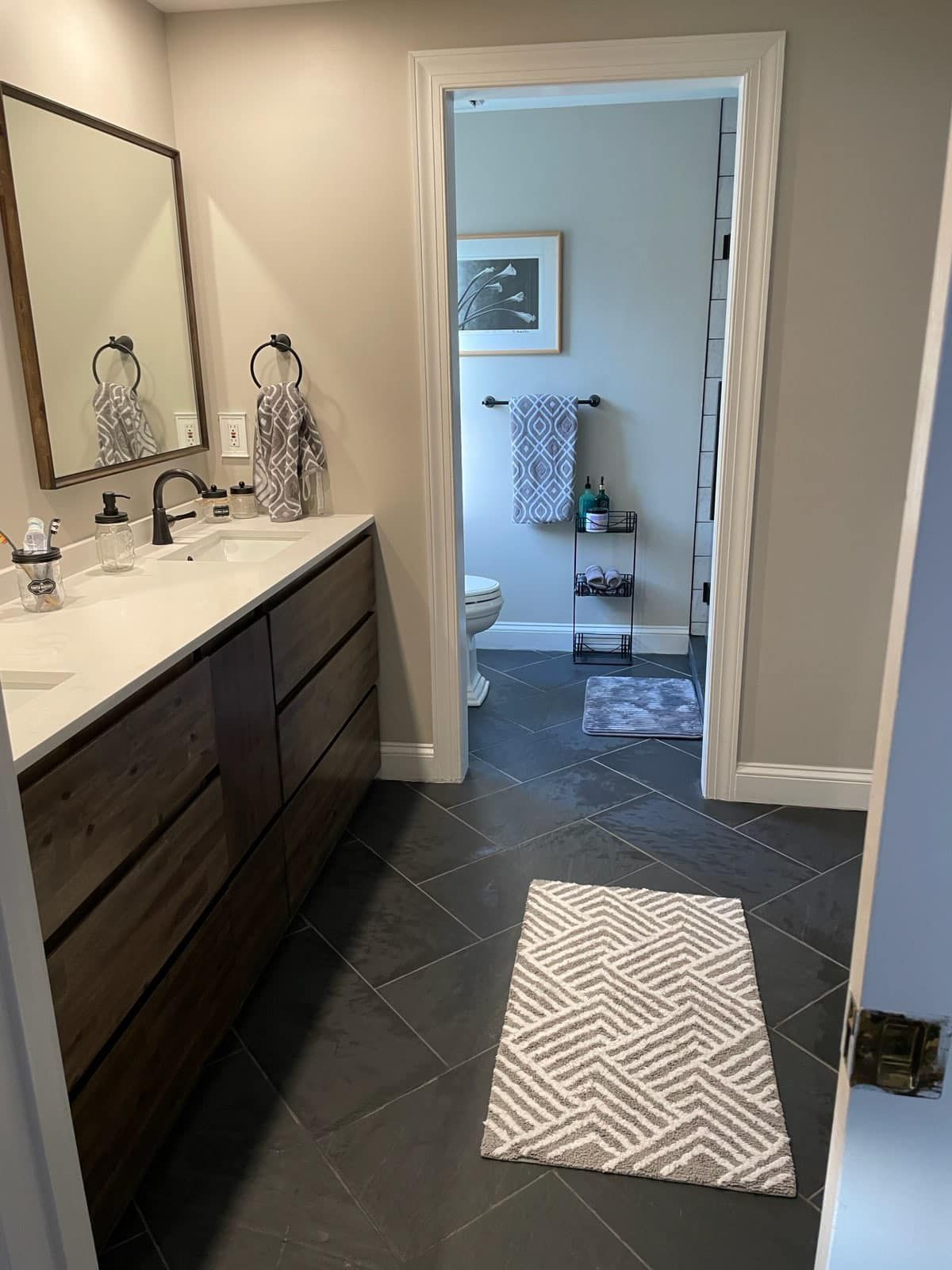 A bathroom with two sinks , a mirror and a rug.