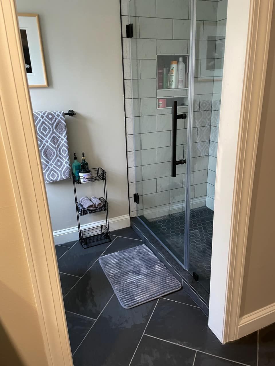 A bathroom with a walk in shower and a rug on the floor.