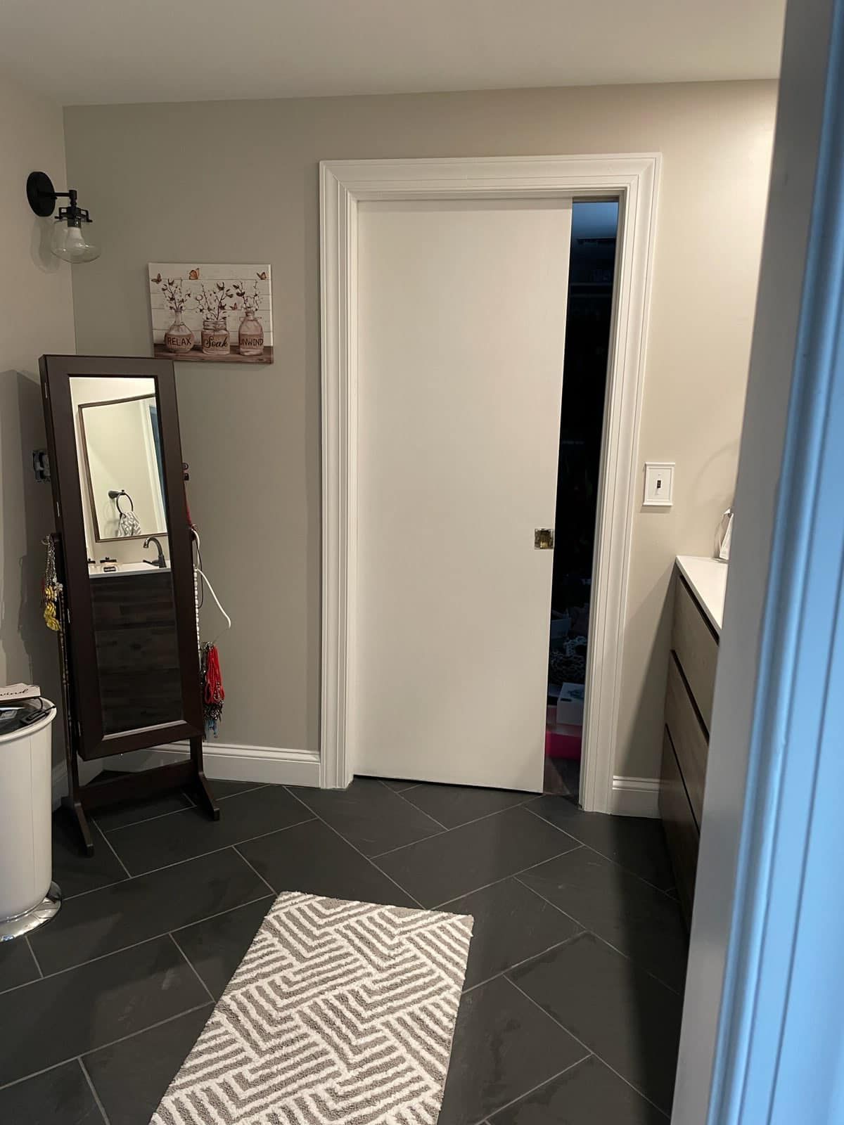 A bathroom with a sliding door , a mirror , and a rug.