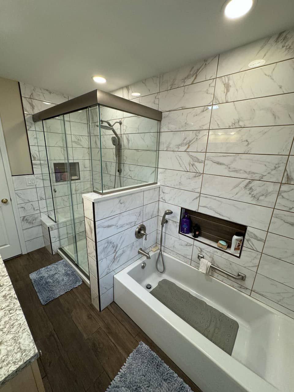 A bathroom with a bathtub , shower , and marble walls.
