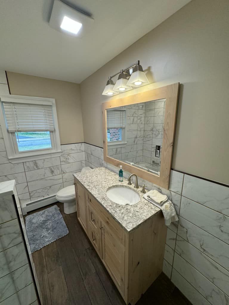 A bathroom with a sink , toilet and mirror.