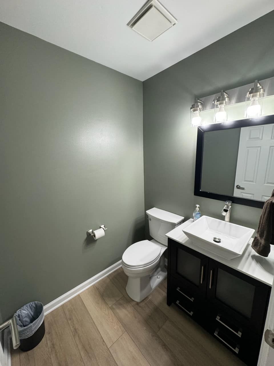 A bathroom with a toilet , sink and mirror.