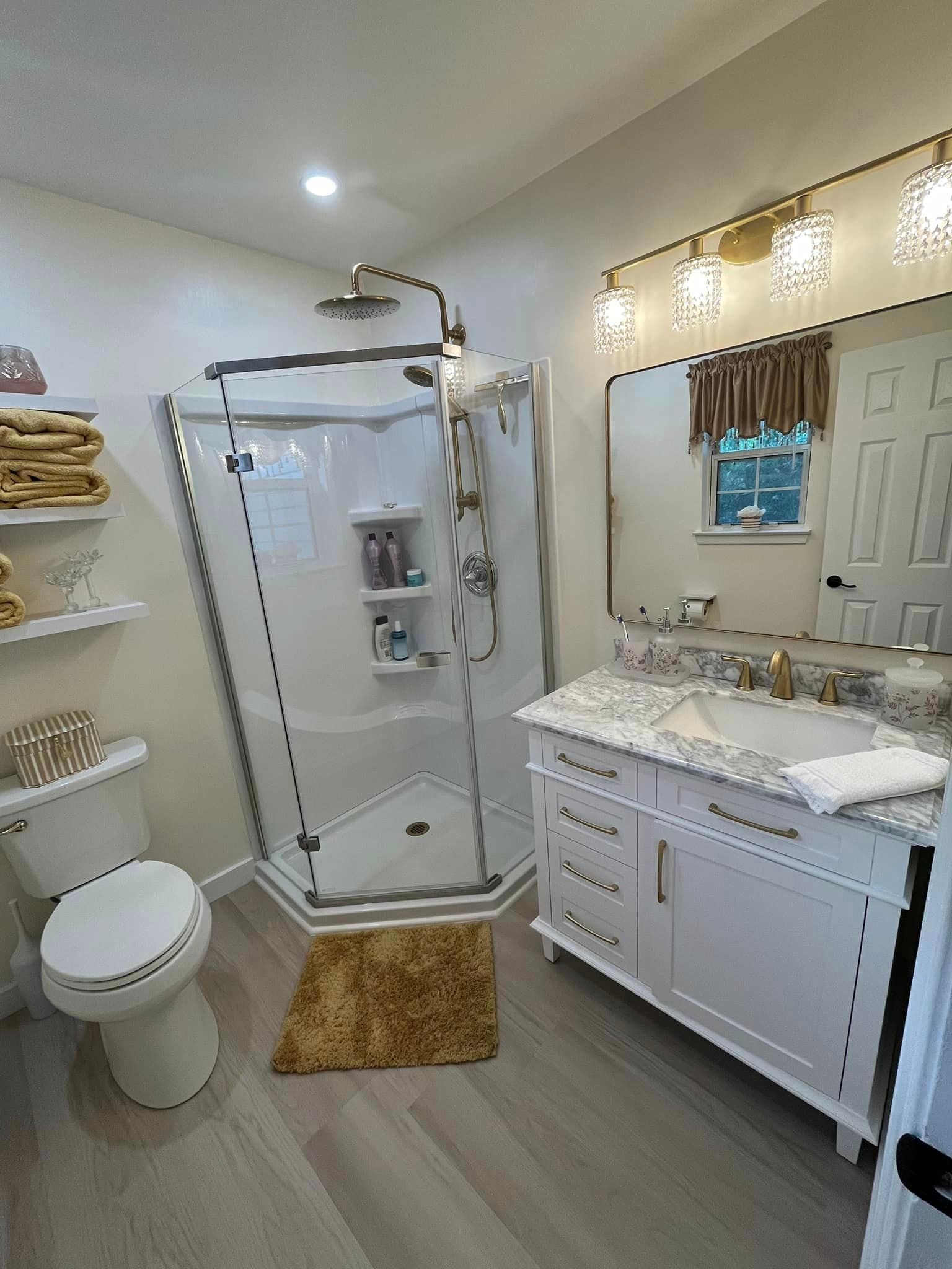 A bathroom with a toilet , sink , shower and mirror.