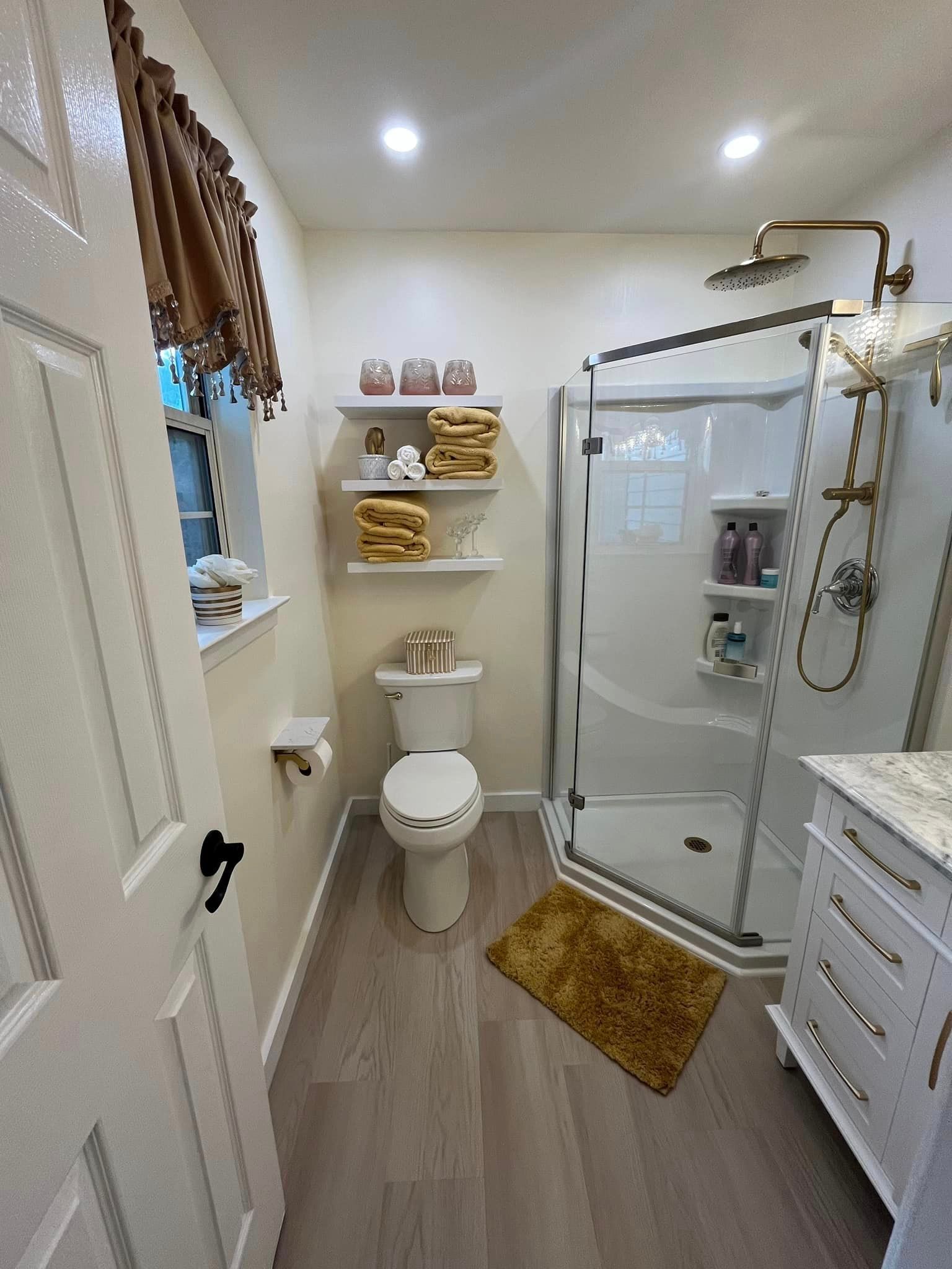 A bathroom with a toilet , sink , shower and rug.