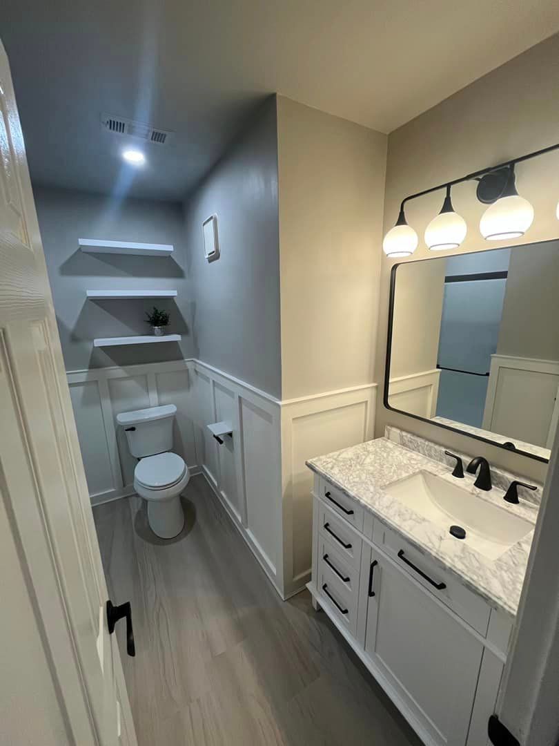 A bathroom with a toilet , sink and mirror.