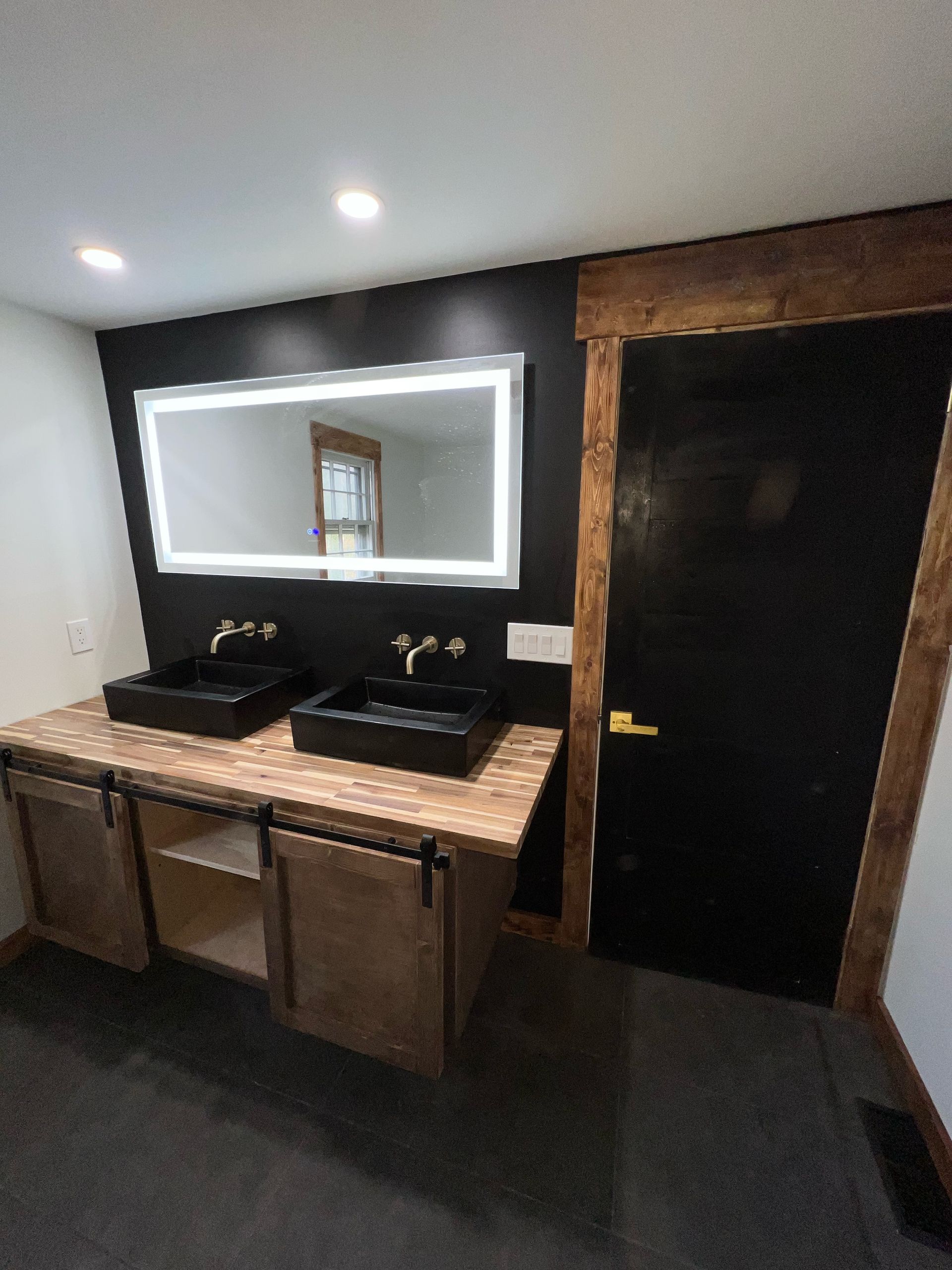 A bathroom with two sinks , a mirror and a door.