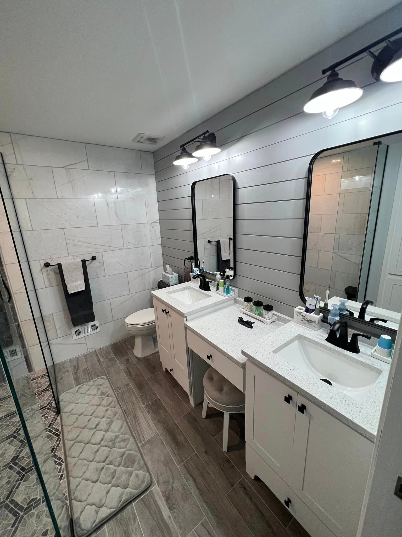 A bathroom with two sinks , a toilet , and two mirrors.