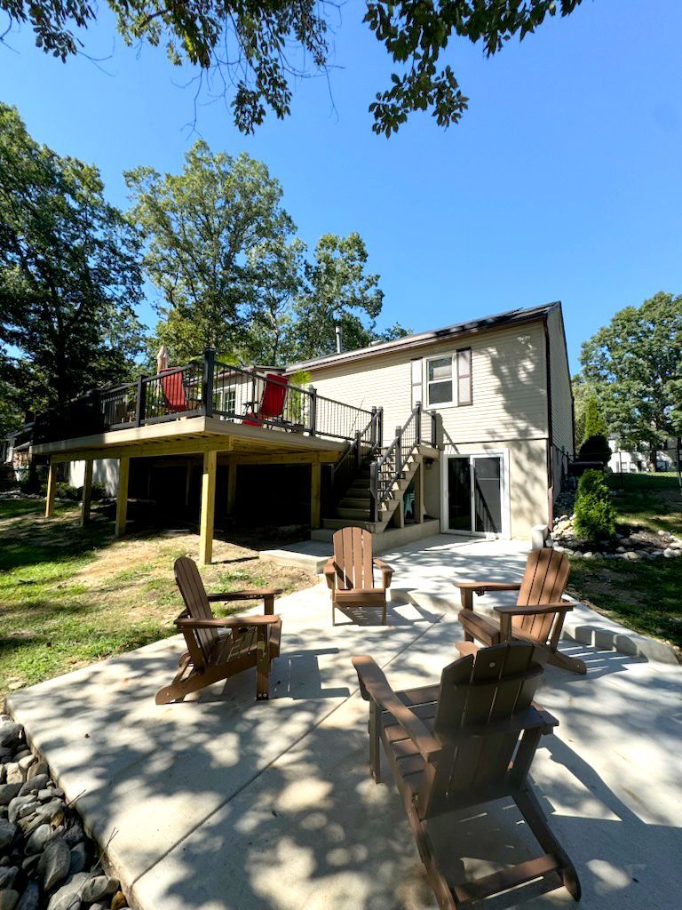 Backyard with deck, chairs around fire pit, two-story house, clear sunny sky.
