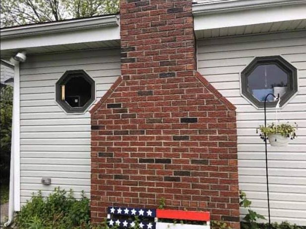 There is a brick chimney on the side of a house.