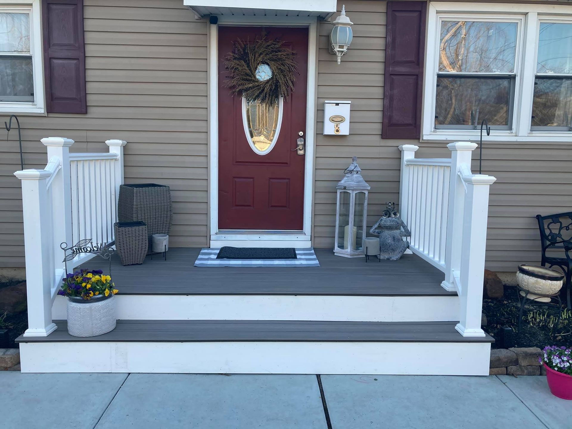 The front porch of a house with a red door and white railing.
