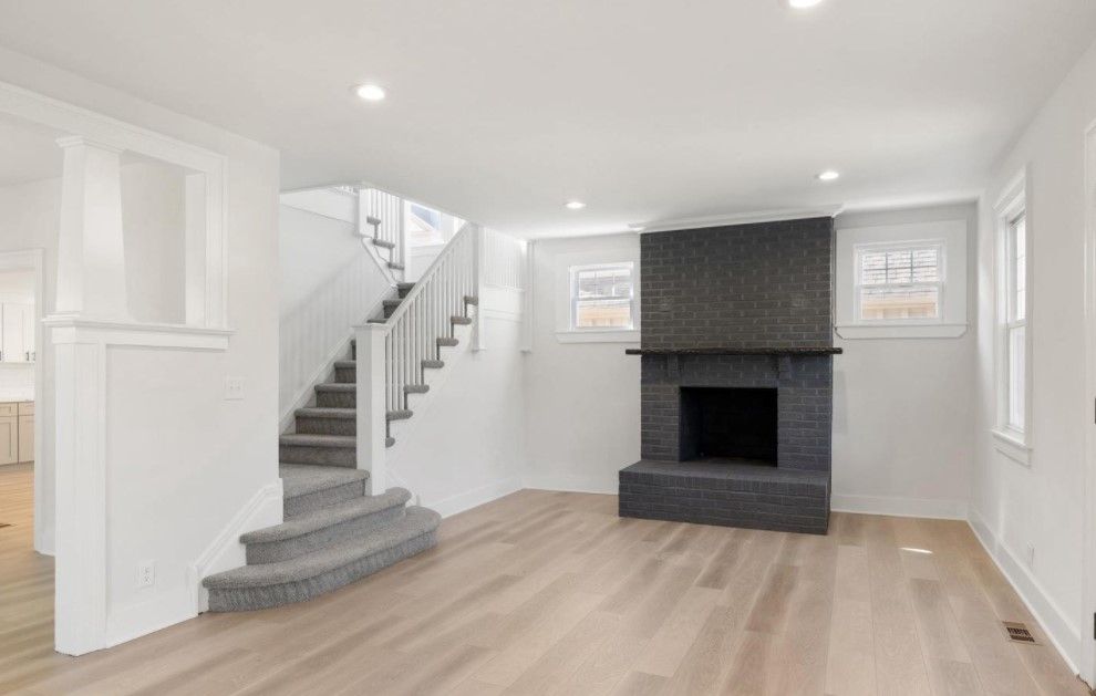 A living room with a fireplace and stairs in a house.