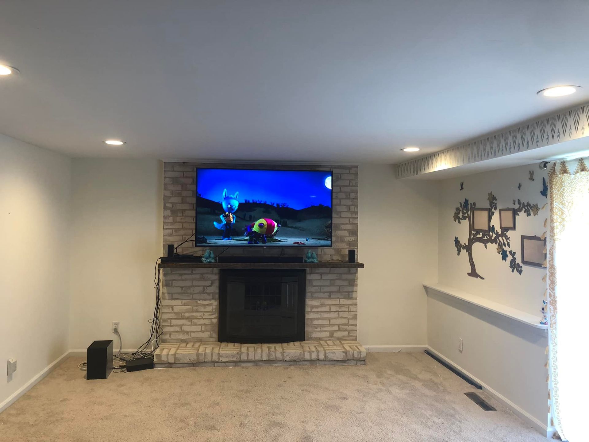 A living room with a fireplace and a flat screen tv on the wall.