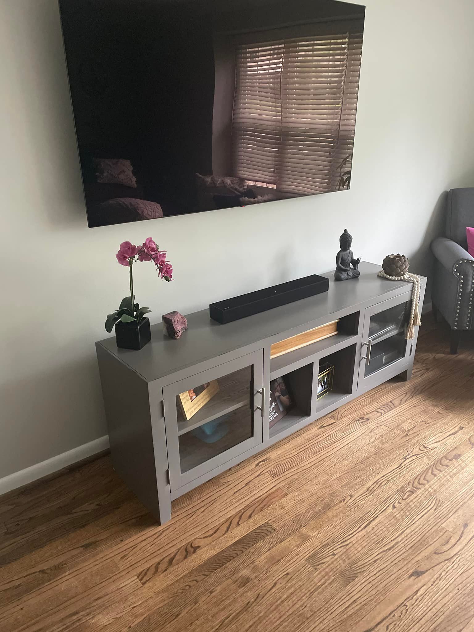 A living room with a gray entertainment center and a flat screen tv on the wall.