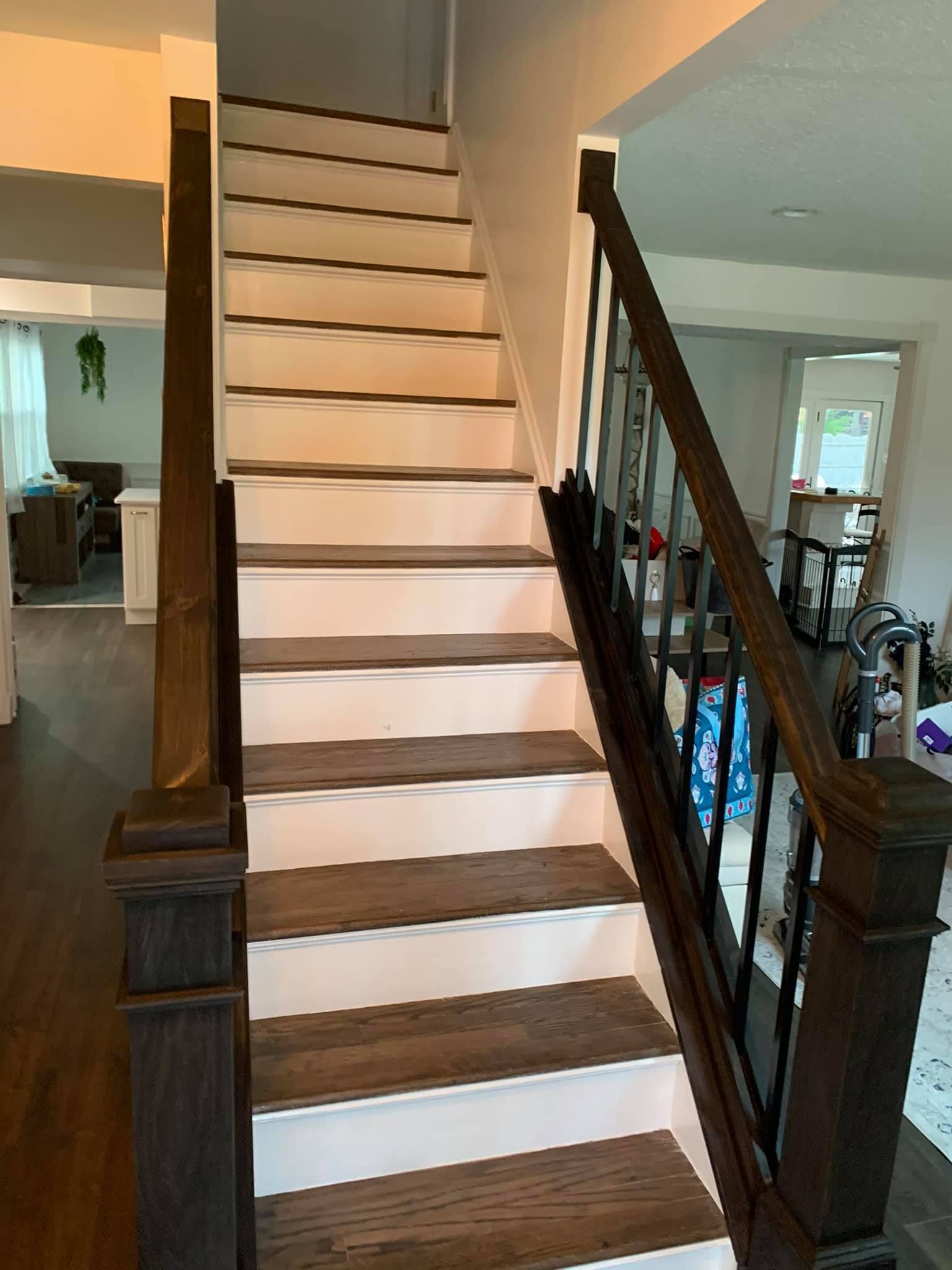 A wooden staircase with white steps and a black railing in a house.