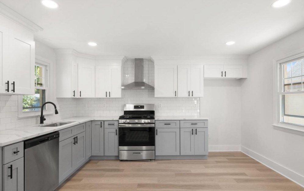 An empty kitchen with white cabinets and stainless steel appliances.