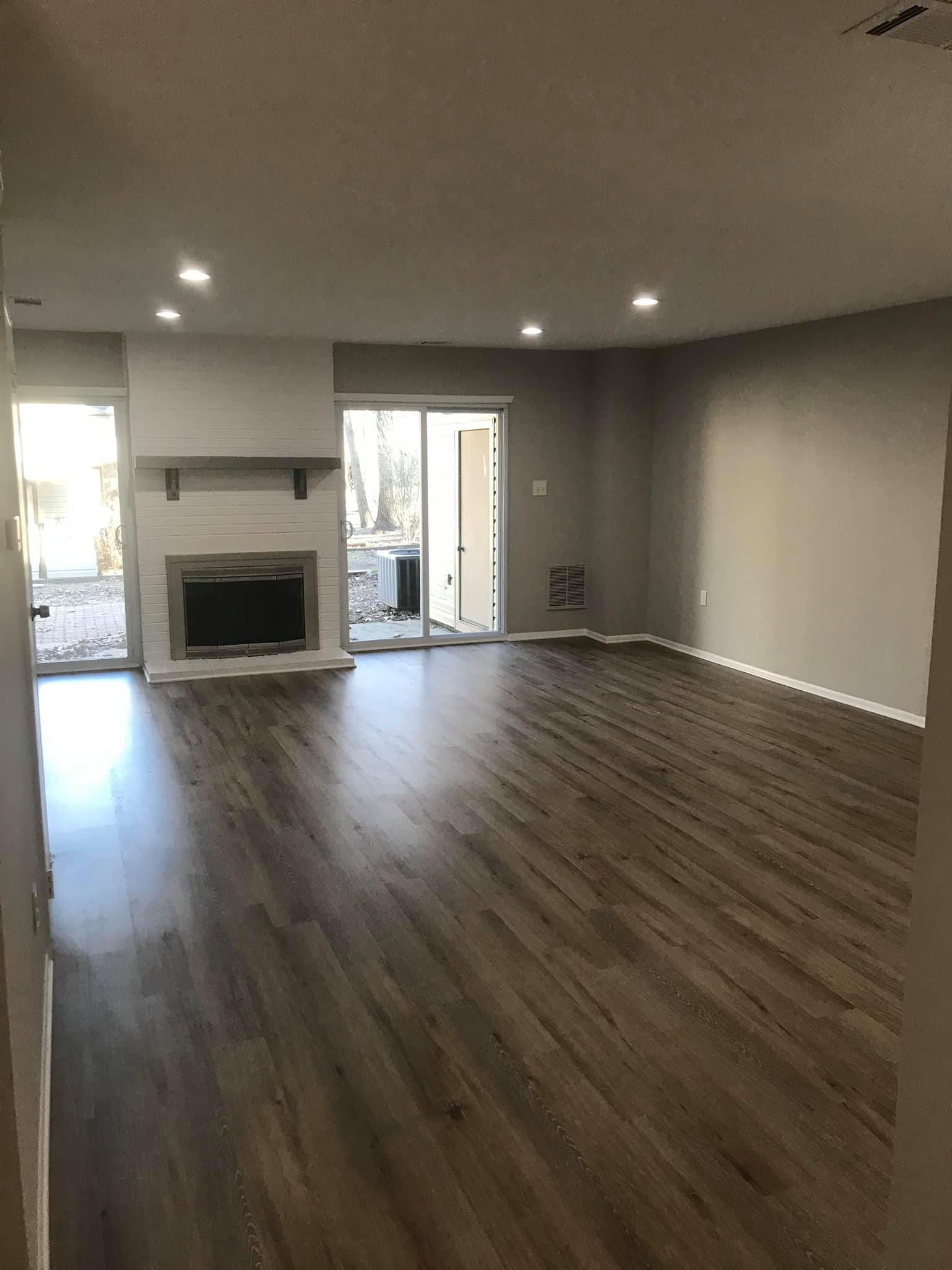 An empty living room with hardwood floors and a fireplace.