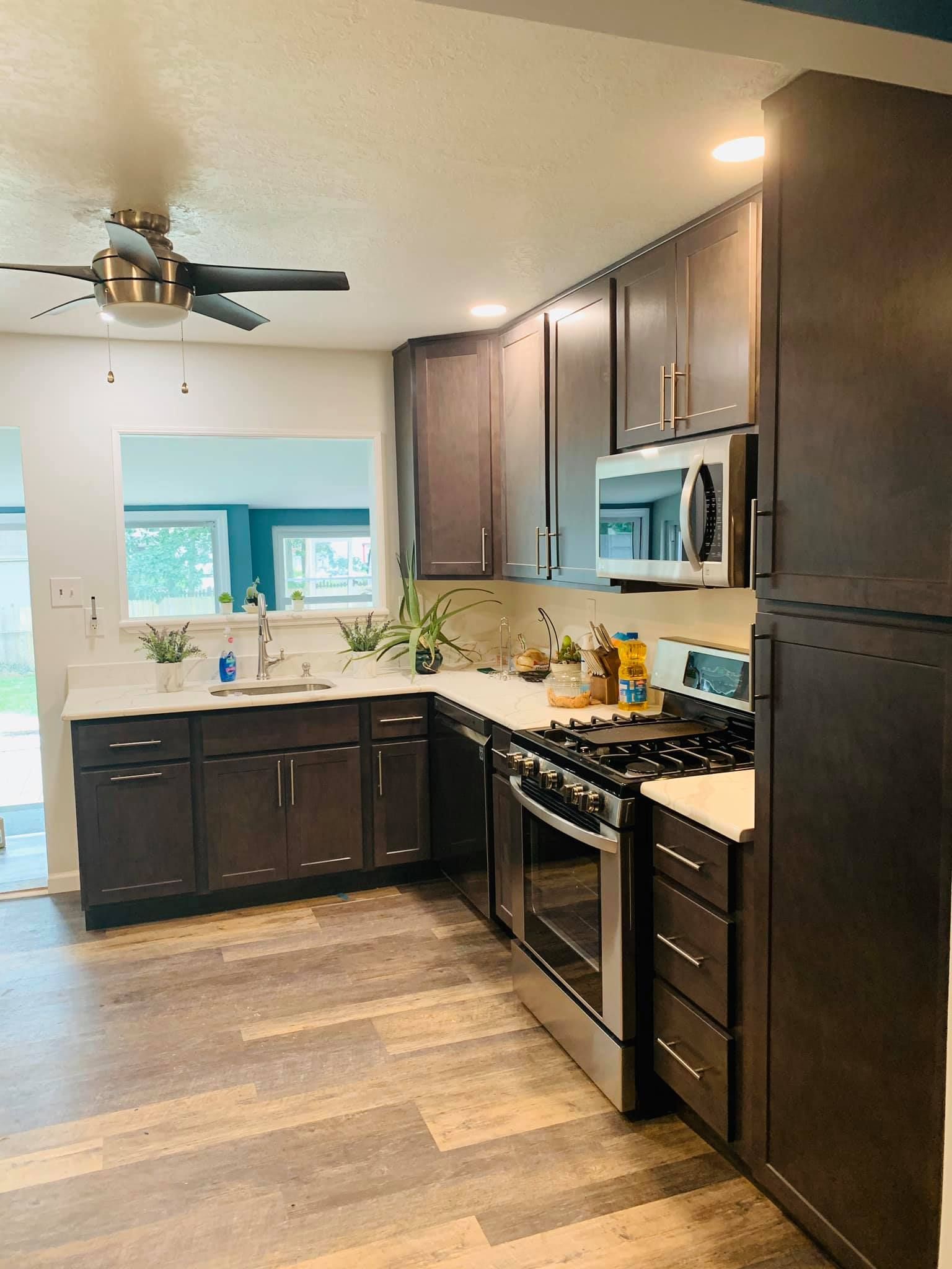 A kitchen with stainless steel appliances , wooden cabinets and a ceiling fan.