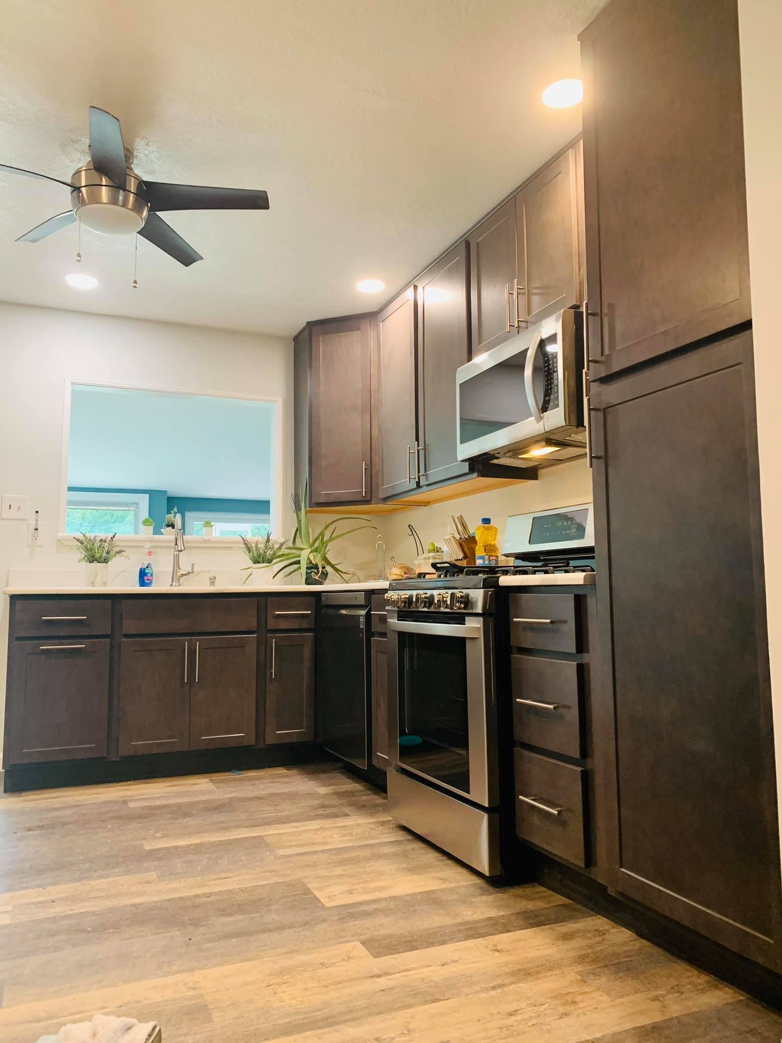 A kitchen with stainless steel appliances , wooden cabinets and a ceiling fan.
