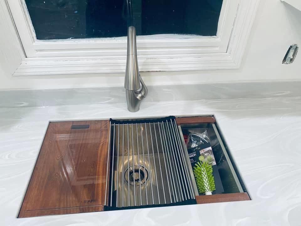 A kitchen sink with a stainless steel faucet and a wooden counter top.