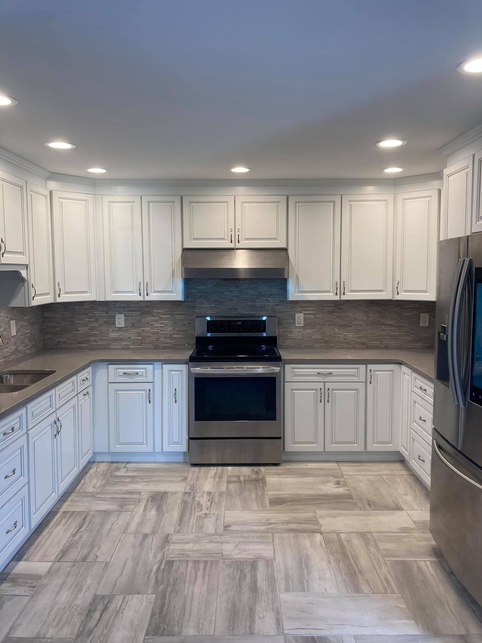 A kitchen with white cabinets , a stove , a refrigerator , and a sink.