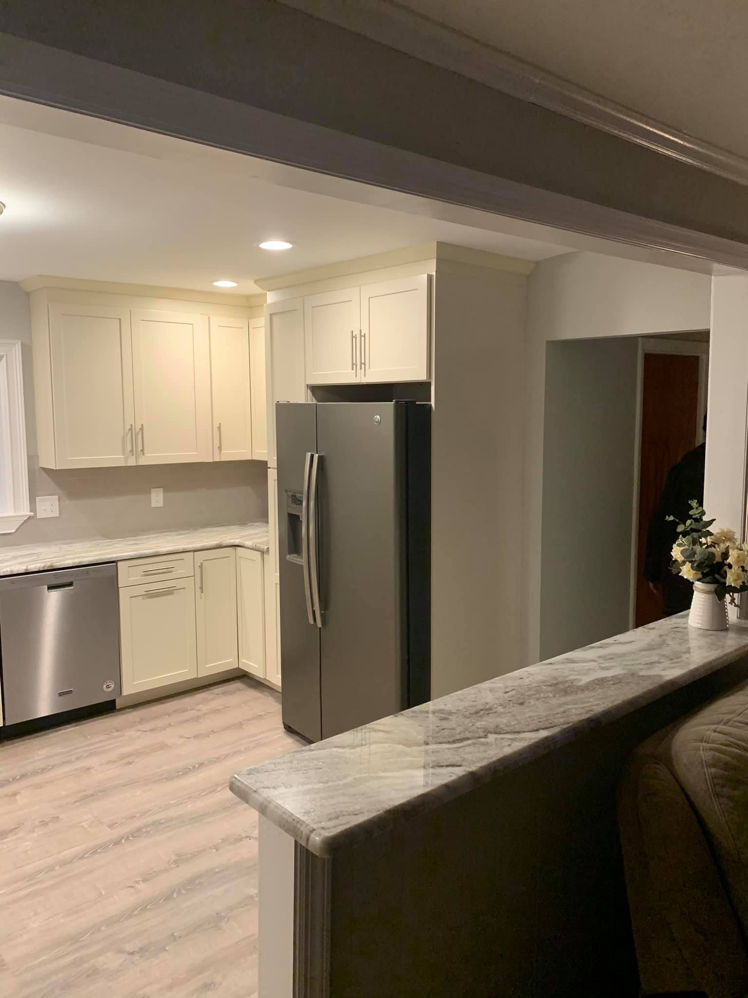A kitchen with white cabinets and a stainless steel refrigerator