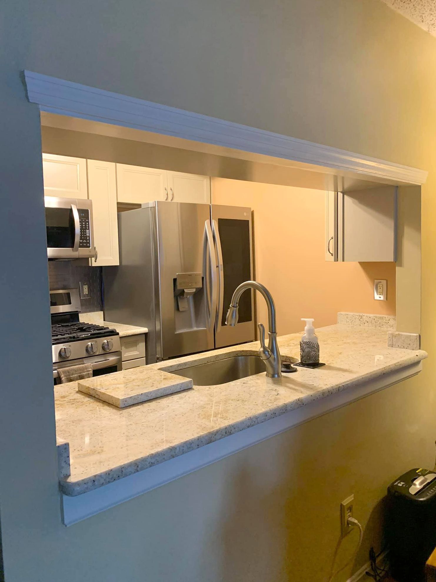 A kitchen with a sink , refrigerator , stove and microwave.