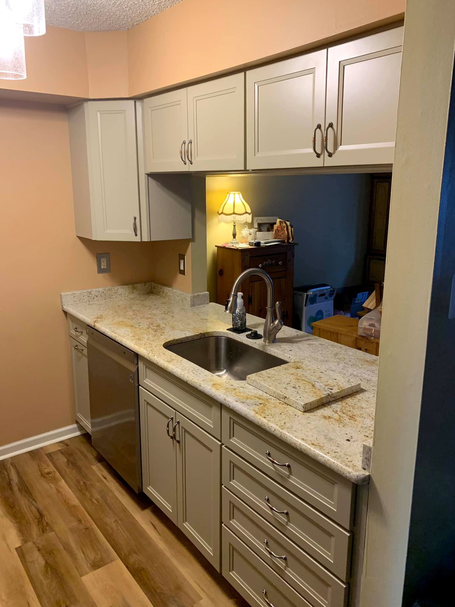 A kitchen with white cabinets , a sink , and a dishwasher.