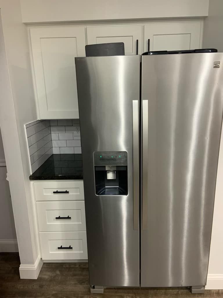 A stainless steel refrigerator is sitting in a kitchen next to a counter.