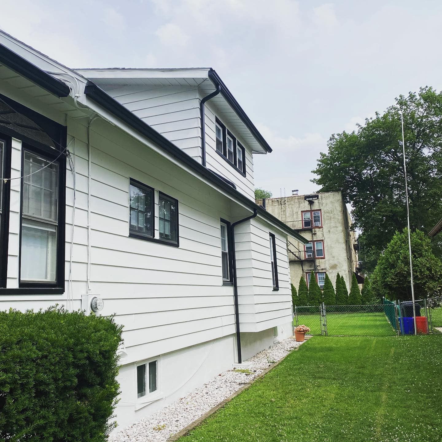 A white house with black trim sits on a lush green lawn
