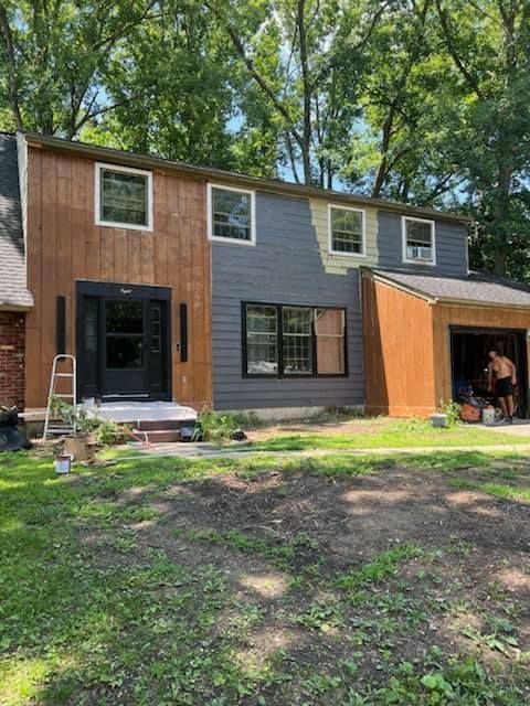 A man is standing in front of a house that is being remodeled.
