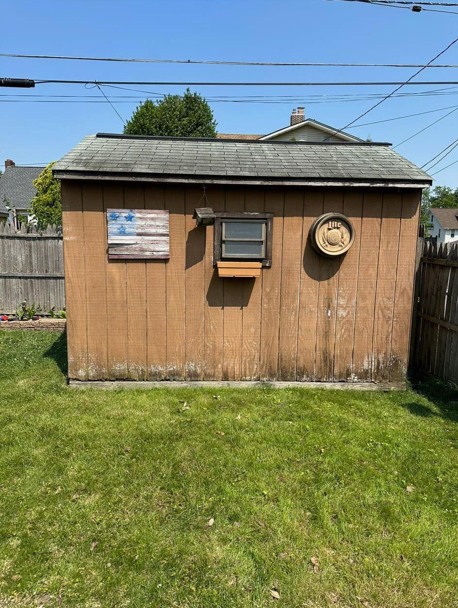 A small wooden shed with an american flag on the side of it.