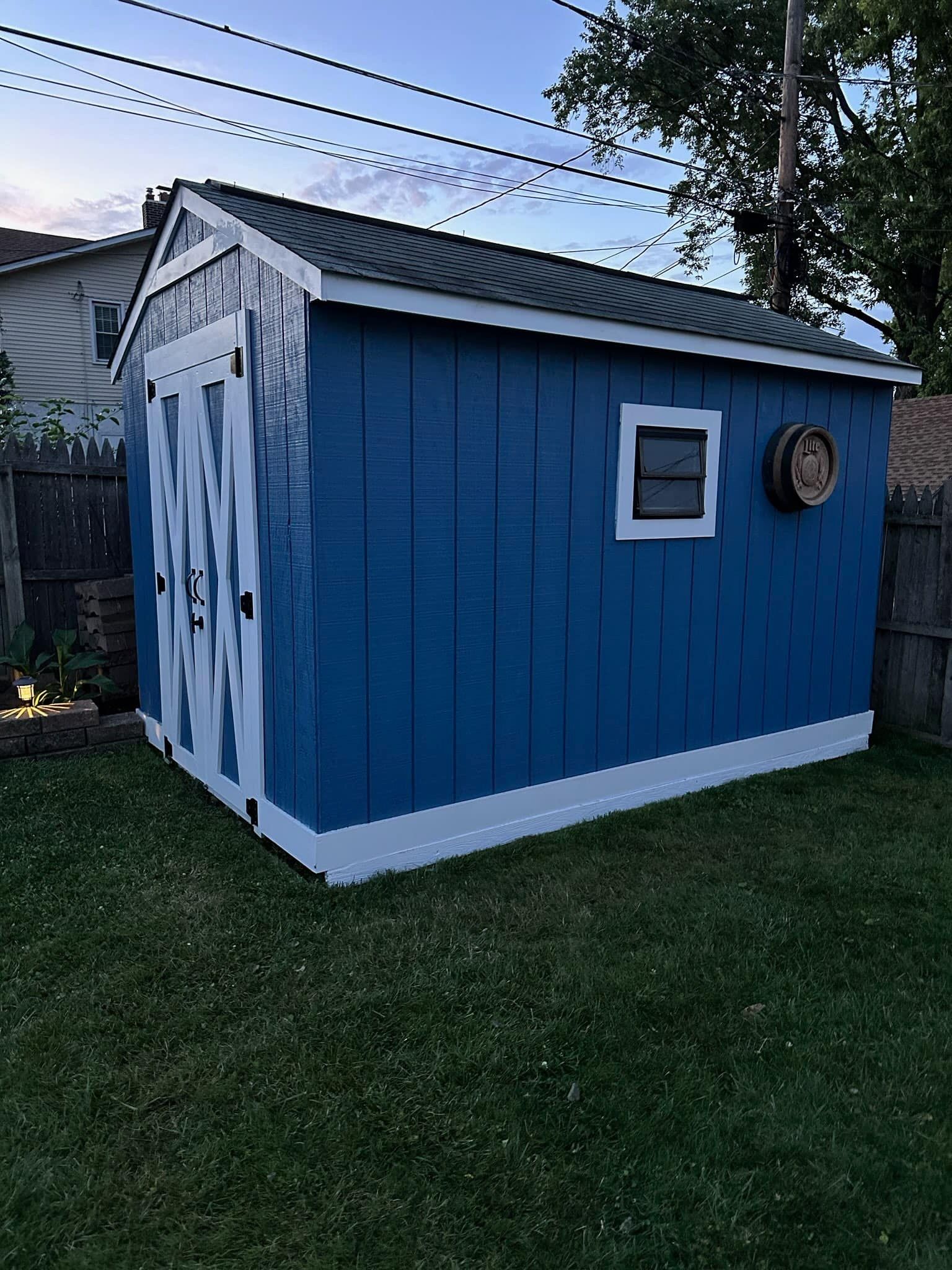 A blue and white shed is sitting on top of a lush green lawn.