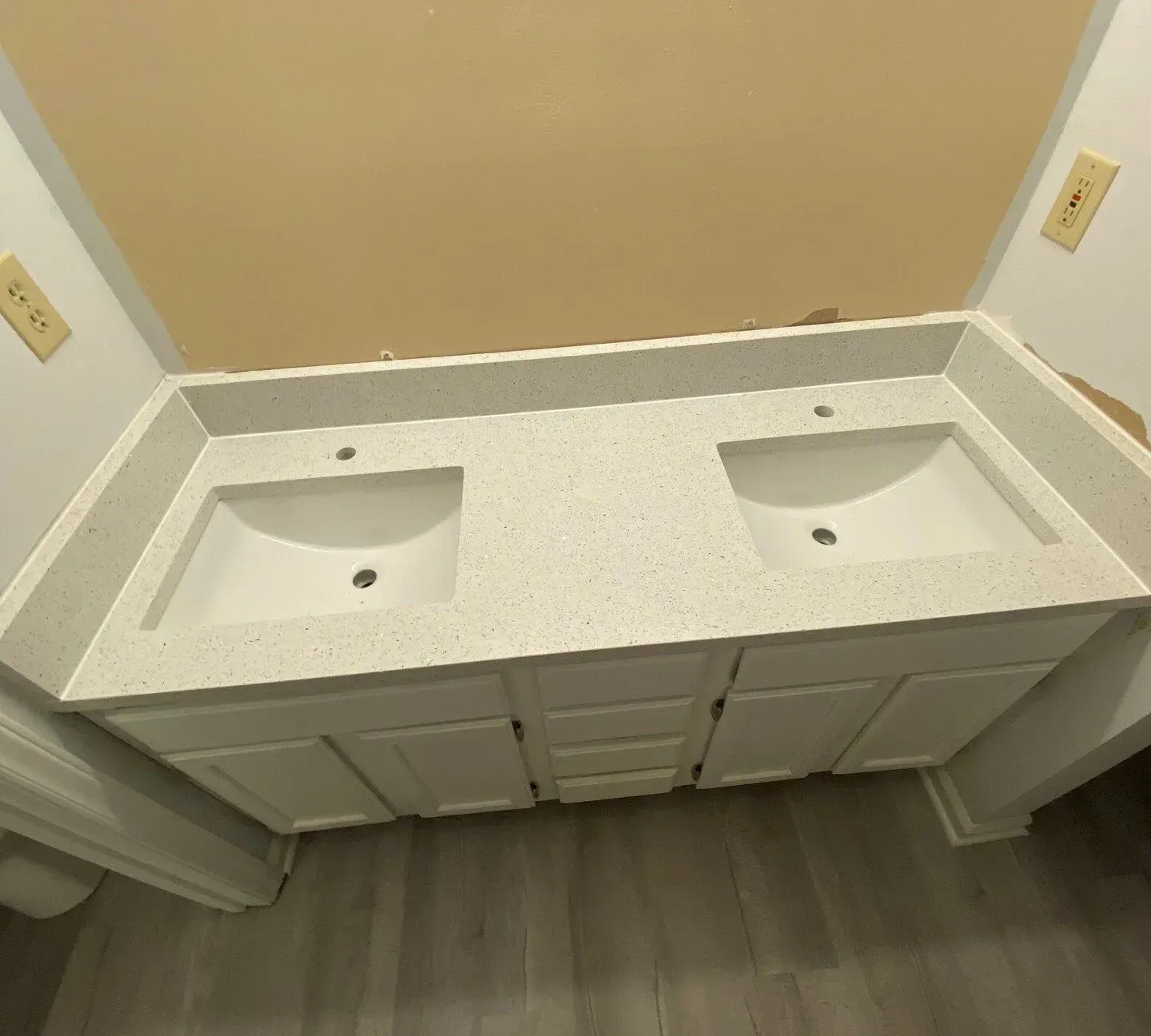 White double vanity with light speckled countertop and two sinks, with drawers and cabinets beneath.