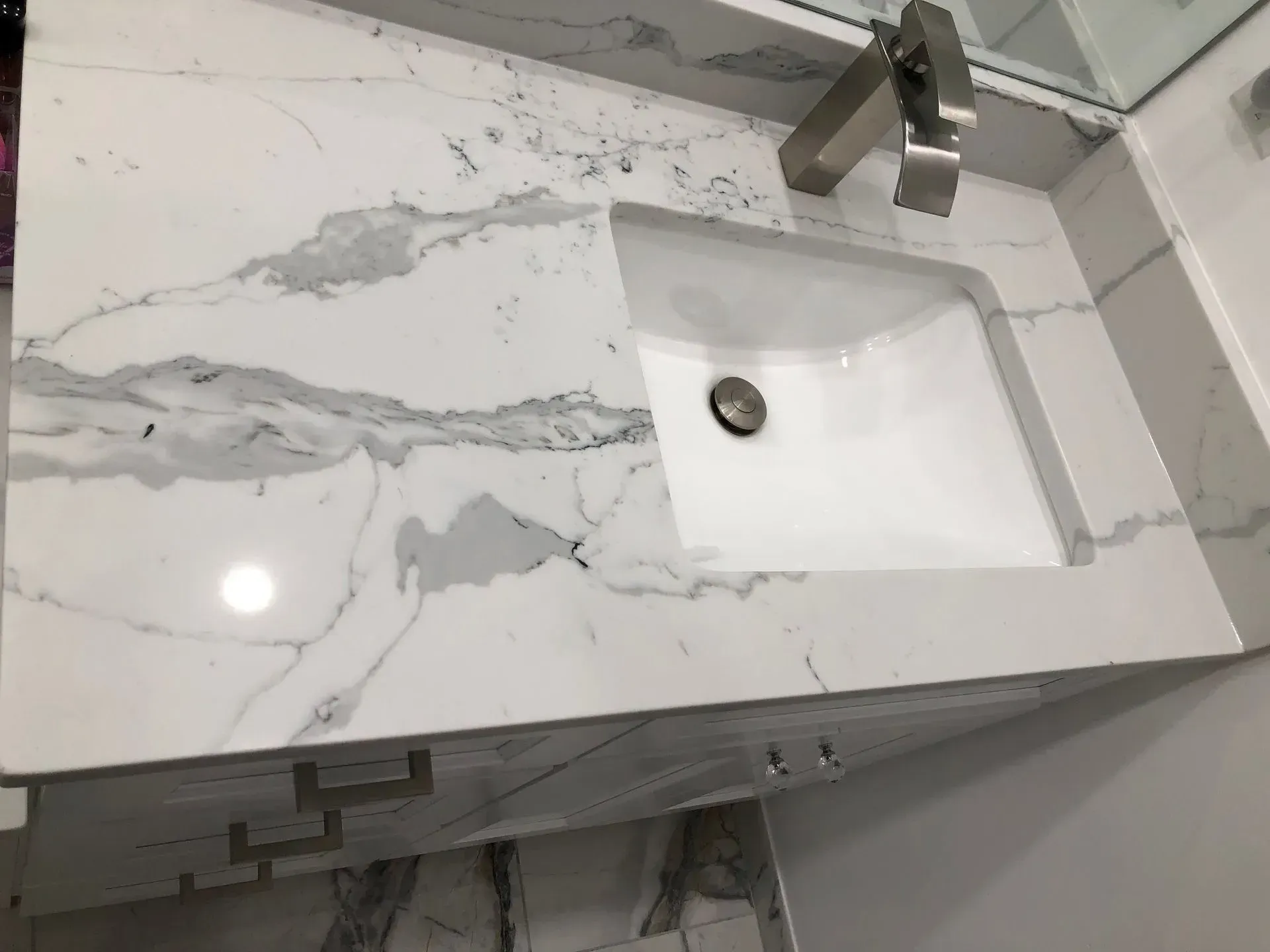 White marble bathroom countertop with sink and faucet.