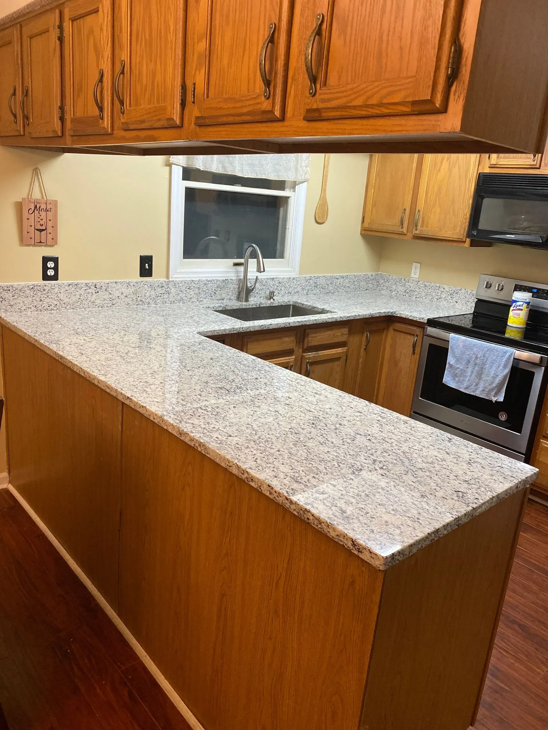 U-shaped kitchen with light granite countertop, wood cabinets, and stainless steel appliances.