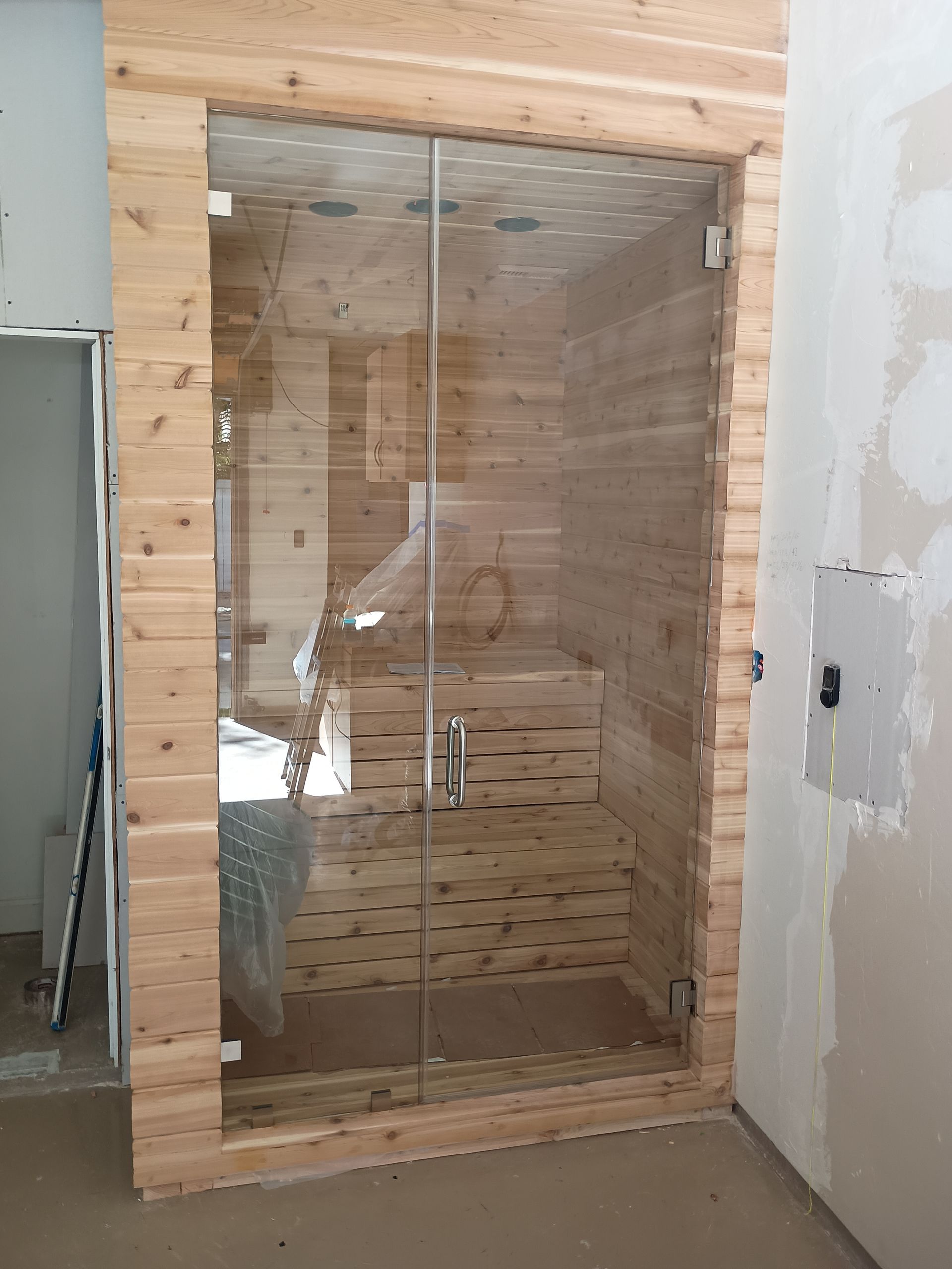 Framed glass shower door with wooden interior, under construction.