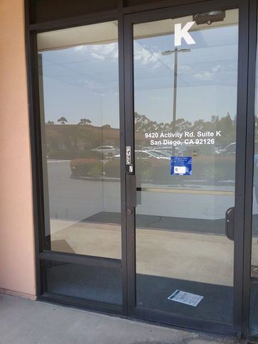 Glass doors of a building entrance, unit K, with a sign, in San Diego, CA.