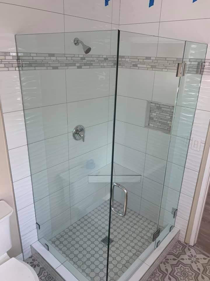 Glass shower enclosure with white tile and mosaic accents.